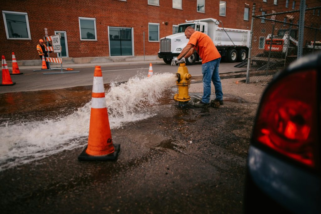 a man in an orange shirt is working on a fire hydrant